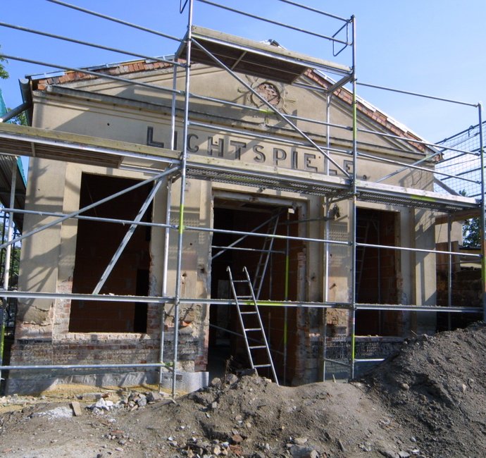 Ein Gebäude im Bau mit dem Schriftzug "Lichtspiele" und einem Baugerüst davor