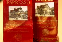 Auf einem Tisch stehen zwei rote Tüten, eine Tüte ist mit Kaffee beschriftet, die andere mit Espresso.