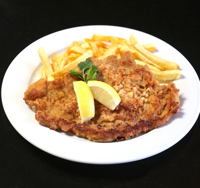 Teller mit Wiener Schnitzel, Pommes Frites und zwei Zitronenspalten
