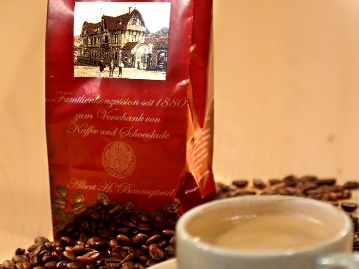 Eine Tasse Kaffee, einige lose Kaffeebohnen und eine Tüte mit Kaffeebohnen