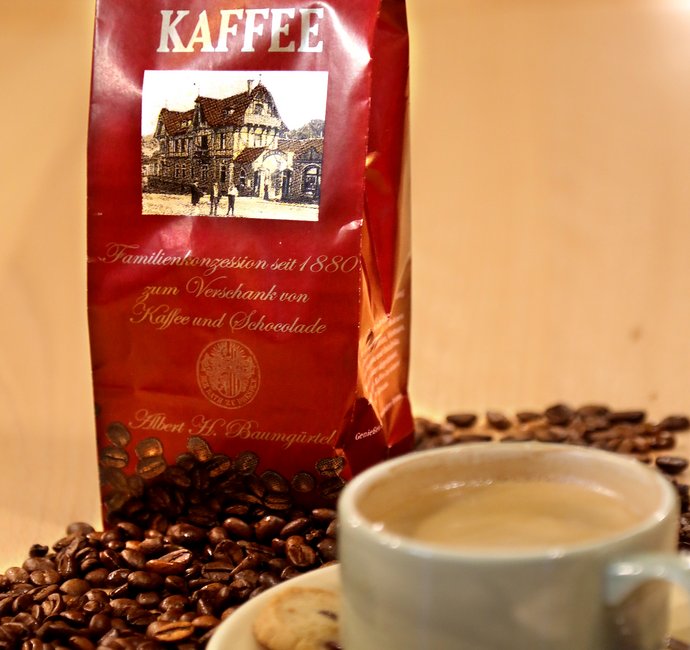 Eine Tasse Kaffee, einige lose Kaffeebohnen und eine Tüte mit Kaffeebohnen