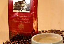 Eine Tasse Kaffee, einige lose Kaffeebohnen und eine Tüte mit Kaffeebohnen