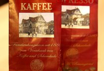 Zwei Tüten mit Kaffeebohnen, mit dem Schriftzug "SchillerGarten. Kaffee. Familienkonzession seit 1880 zum Verschank von Kaffee und Schokolade